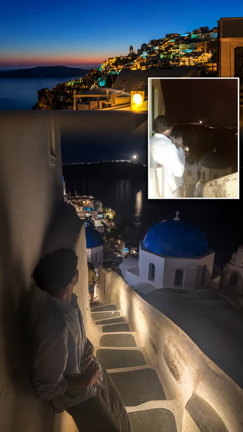 Oia at night with blue domed churches lit above the caldera